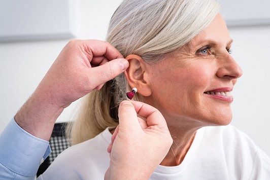 Ältere Frau bekommt modernes Hörgerät angepasst, Hörakustiker berät zur Hörhilfe.